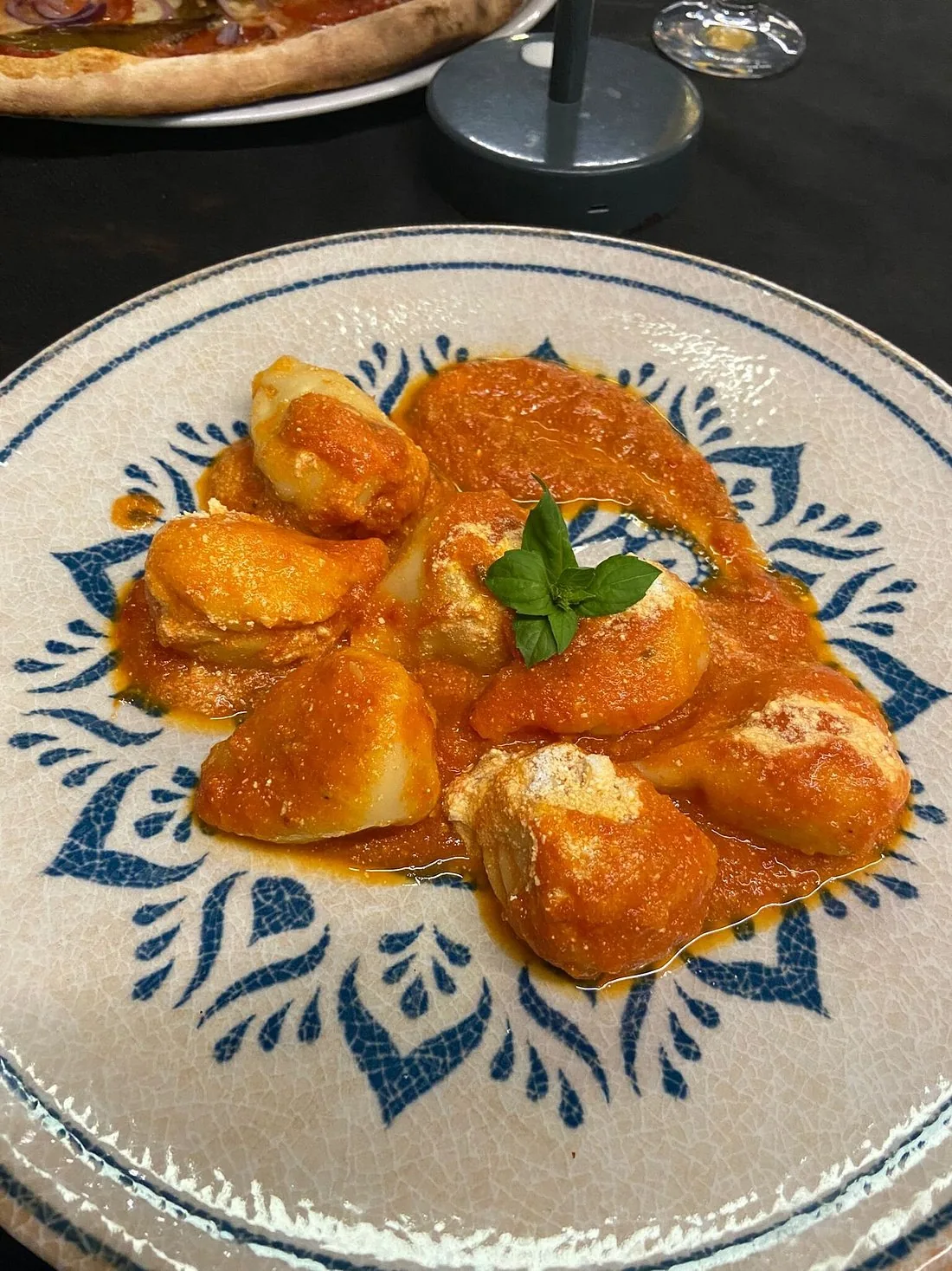 Gnocchi al pomodoro con basilico, serviti in un piatto decorato a mano.