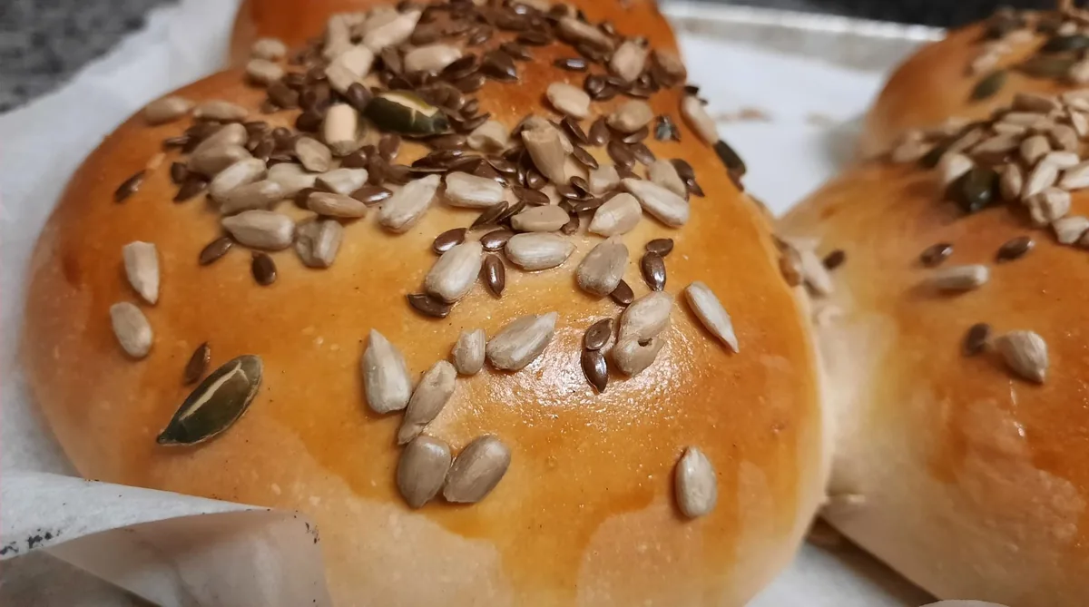 Panini di pane fatto in casa appena sfornati, con semi di girasole e di zucca sulla crosta.