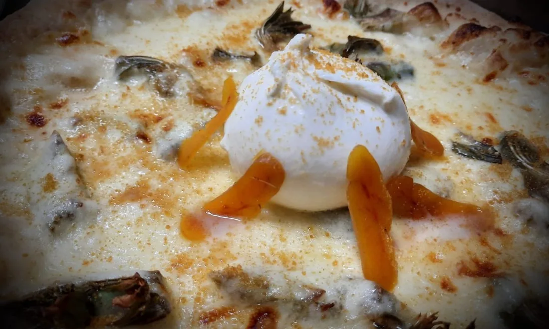 Pizza bianca con carciofi freschi e una burrata al centro.