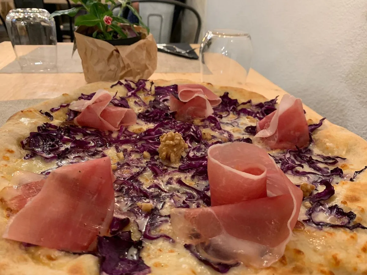 Pizza bianca con rose di prosciutto crudo, cavolo cappuccio viola e noci.