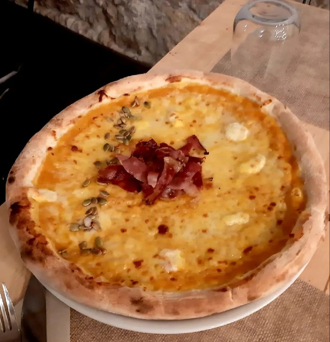 Pizza con crema di zucca, speck croccante e semi di zucca.